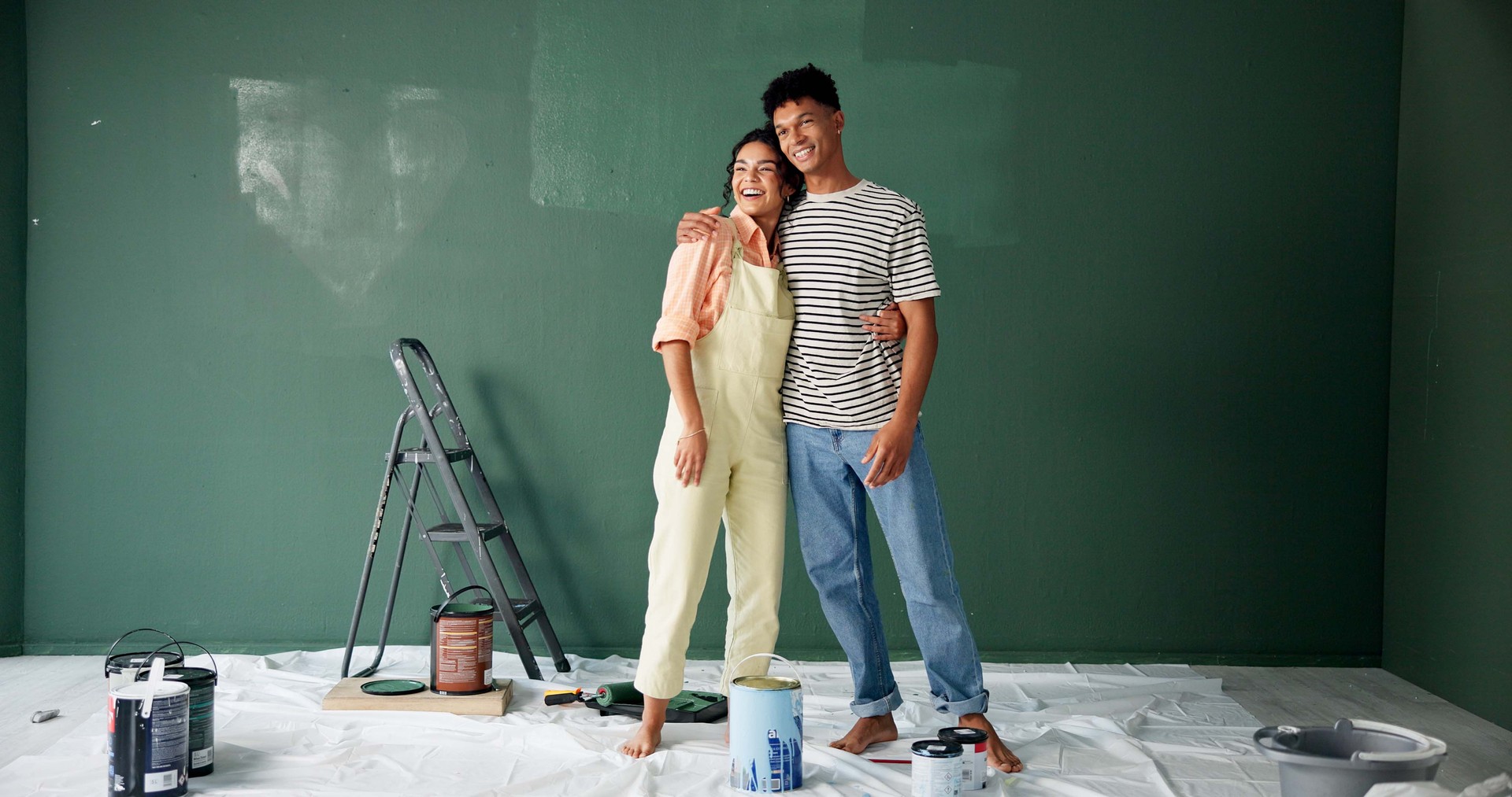 Couple, people and smile with painting wall for house renovations, upgrade and bonding. New home, relationship and happy for makeover for fun with support, care and teamwork for love with diy