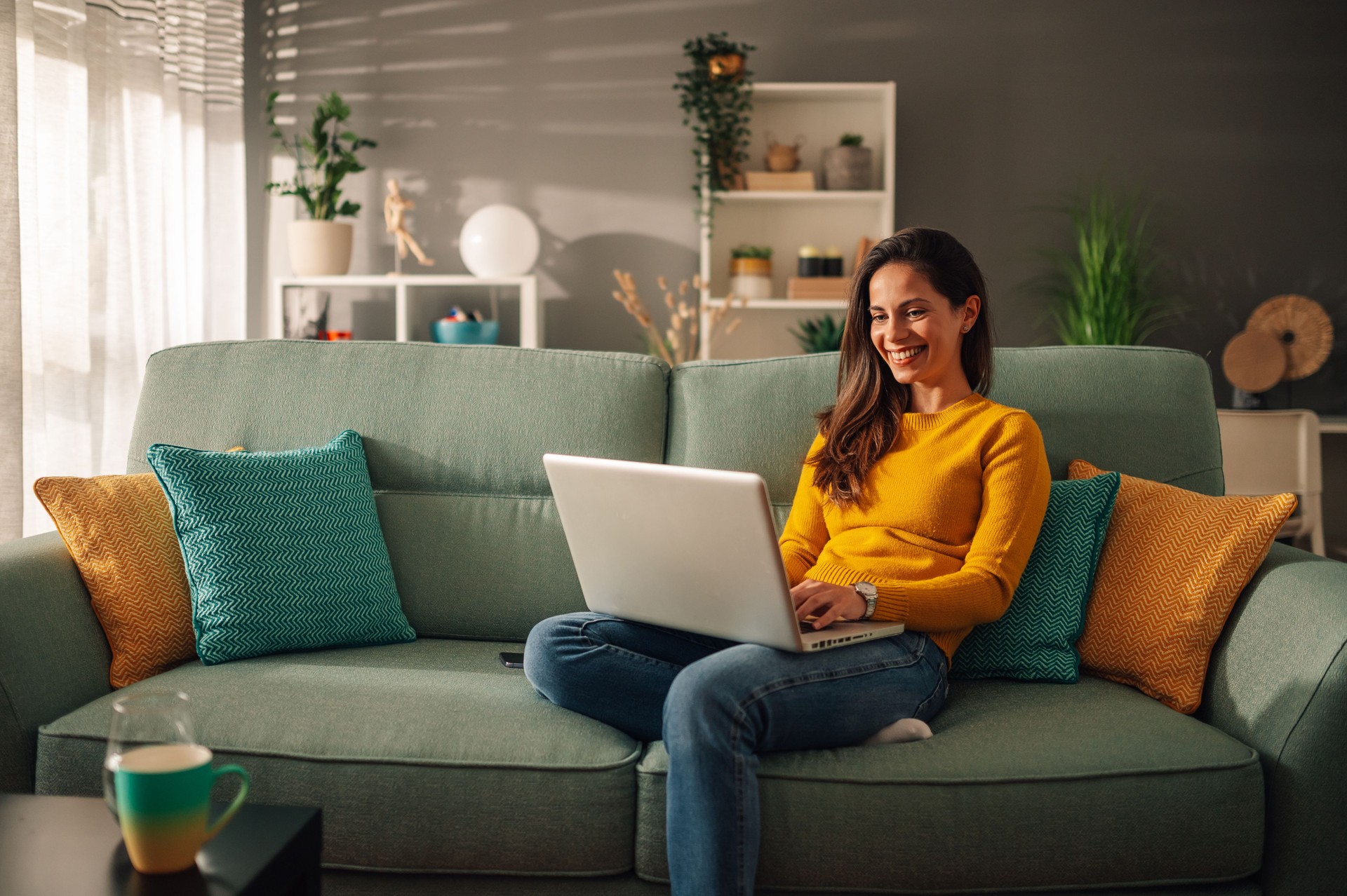 Portrait of a woman using laptop while sitting on a mint couch at home