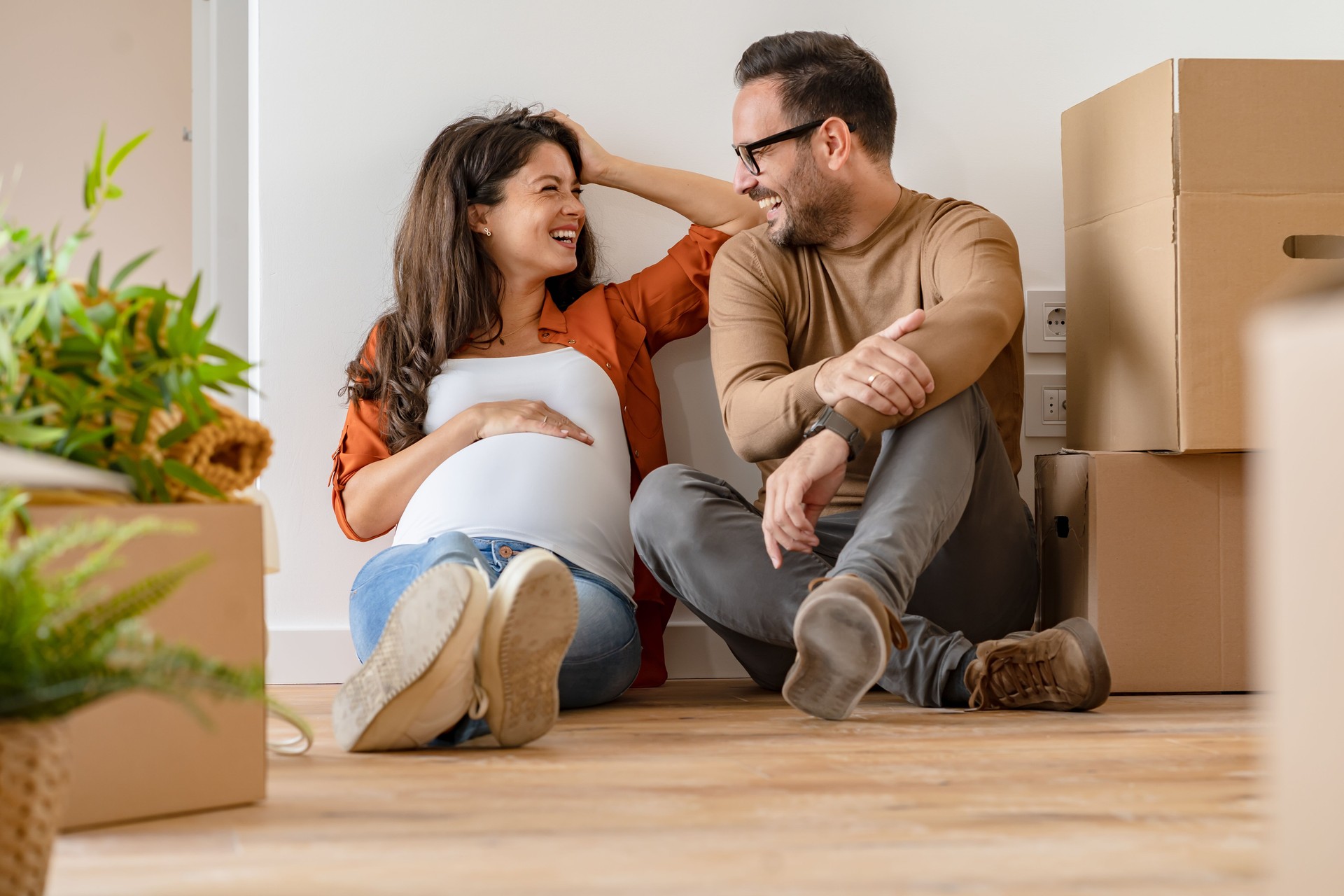 Young happy couple moved into an empty apartment sitting among cardboard boxes