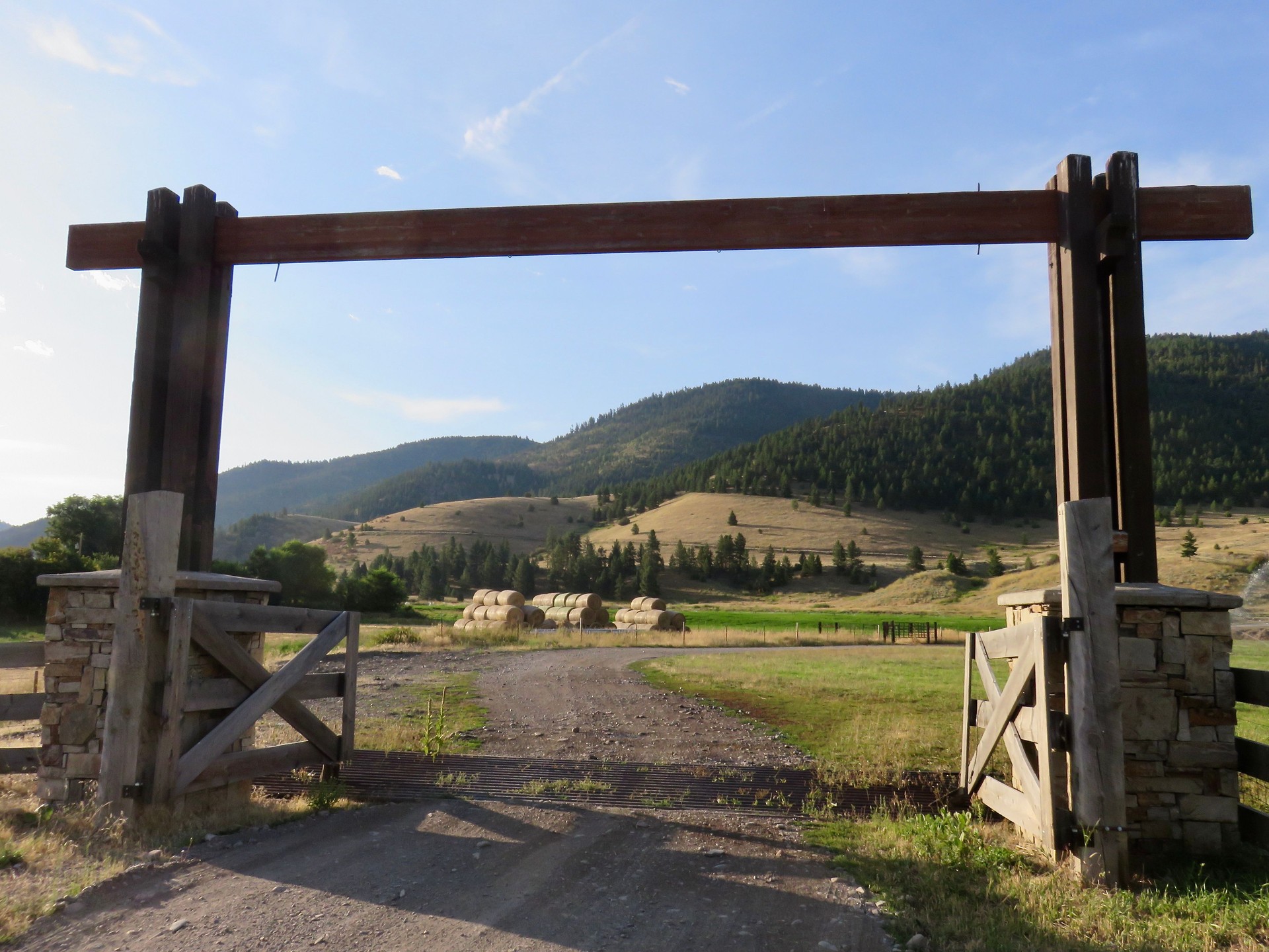 Stone columns support the ranch gate and split rail fence