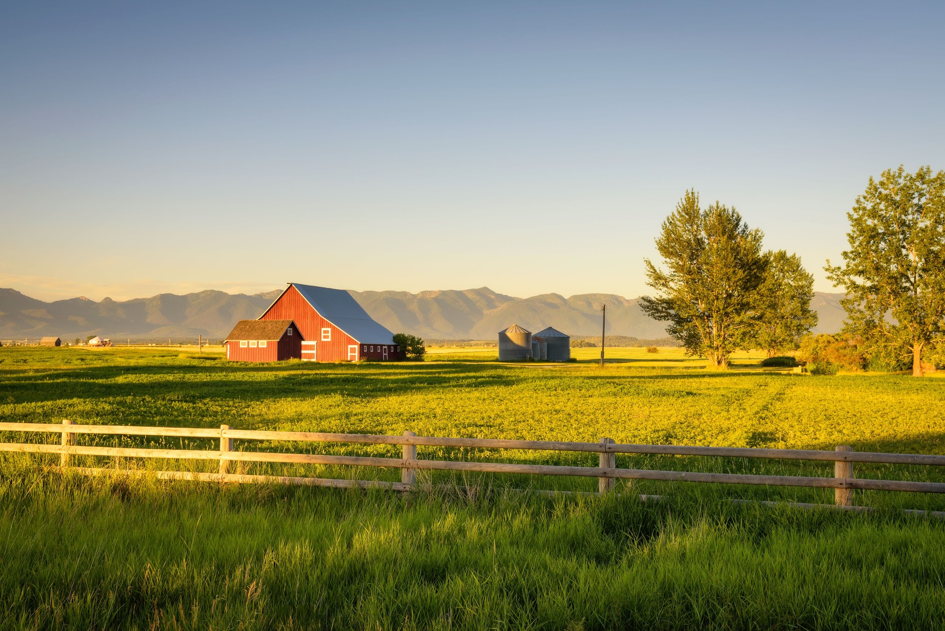 Summer sunset with a red barn in rural Montana and Rocky Mountains